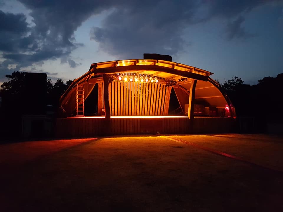 The curved wooden stage glowing with warm amber lights at dusk
